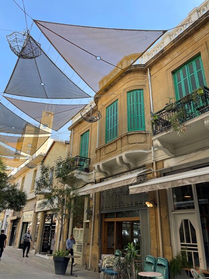 A street with buildings, outdoor seating, and hanging umbrellas. 5