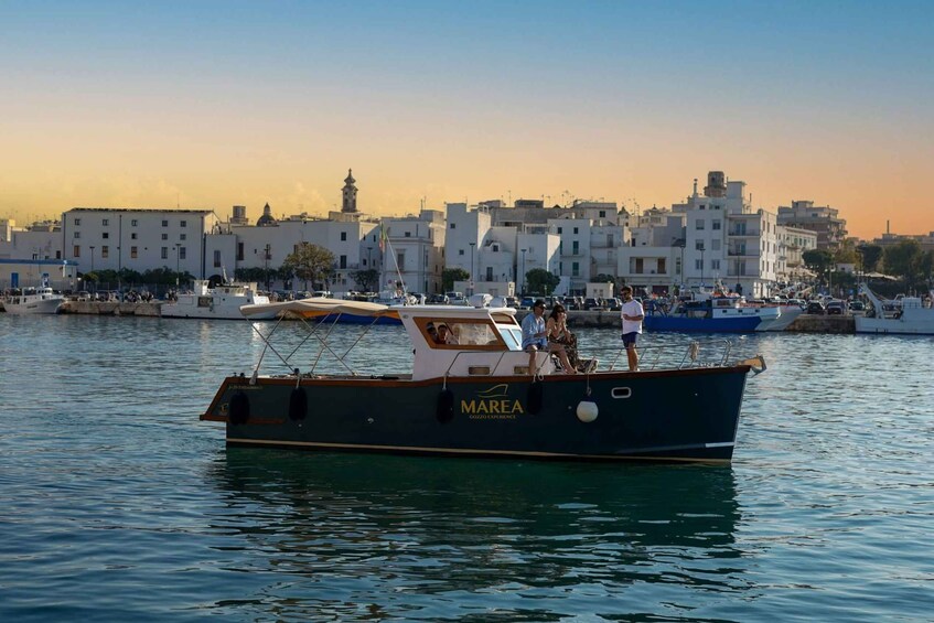A boat named 'MAREA' docked at a marina with a cityscape in the background. 1