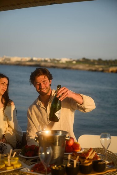 A person pouring a drink from a bottle onto a table with food and a bucket. 5