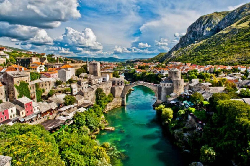 A historic town with a river, a bridge, and mountainous terrain. 1