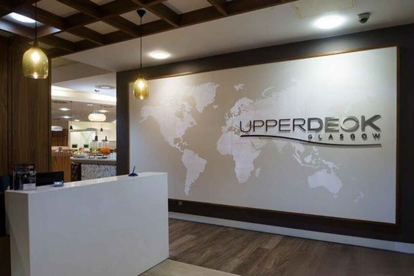 A reception desk with a world map and the text 'UPPERDEOK GLASGOW' on the wall. 1