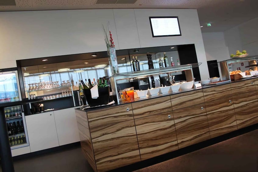 A modern bar area with a marble counter, various bottles, and a display of food items. 5