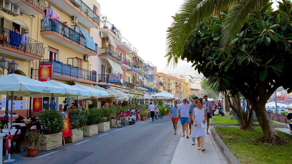 A bustling street with outdoor cafes, pedestrians, and a mix of residential and commercial buildings. 2