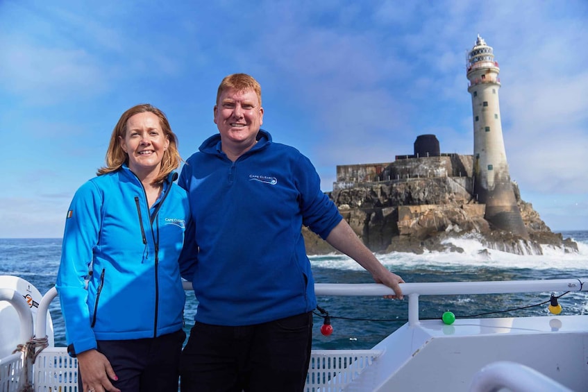 Two people on a boat with a lighthouse in the background. 4