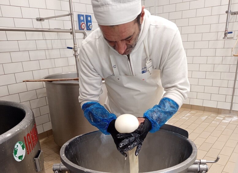 A person in a white uniform and gloves handling a white object in a large metal container. 5