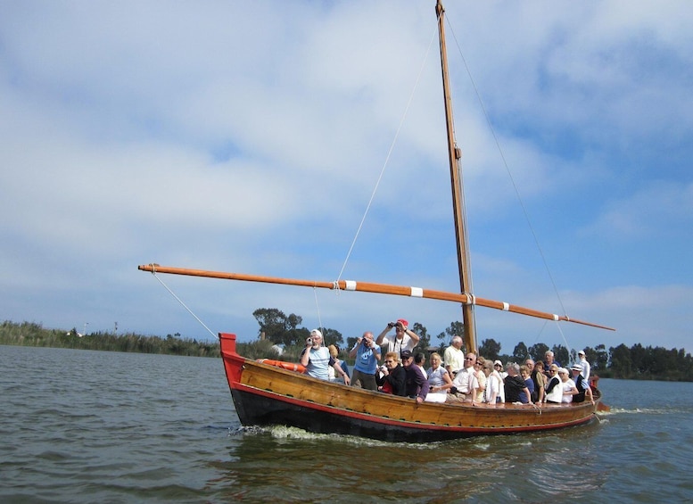 A wooden boat with a sail on a body of water. 1