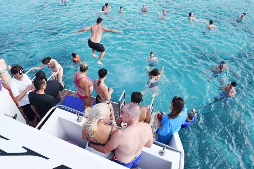 A group of people swimming and playing in a clear blue body of water. 3