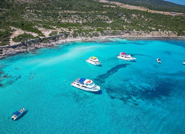 A turquoise sea with boats and a rocky coastline. 2