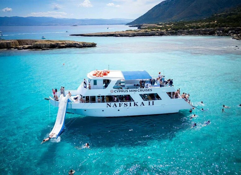 A white boat named 'Nafiska II' with people on board and swimming in the water. 1
