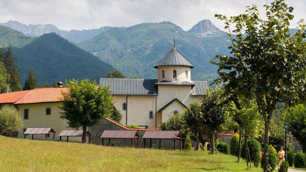 A church with a bell tower, surrounded by a lush green landscape and mountains in the background. 2