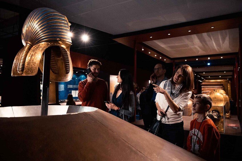 A group of people observing a large, metallic, spiral sculpture in a museum. 3