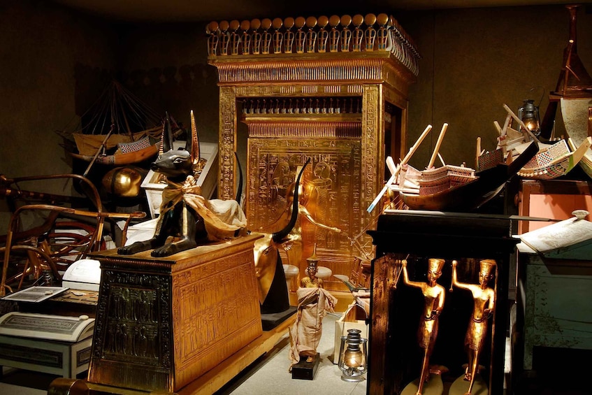A collection of ancient Egyptian artifacts including a golden sarcophagus, a statue of a deity, and hieroglyphic inscriptions. 5