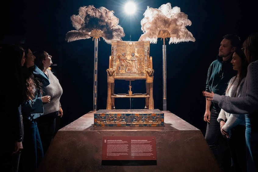 An ancient Egyptian chair with a golden throne and a decorated base, displayed in a museum. 4