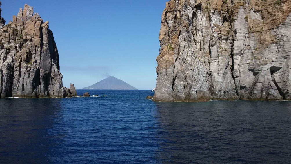 A rocky coastline with a clear view of a distant mountain. 1