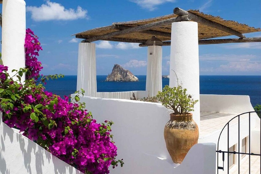 A white building with a view of the sea and a rock formation. 3