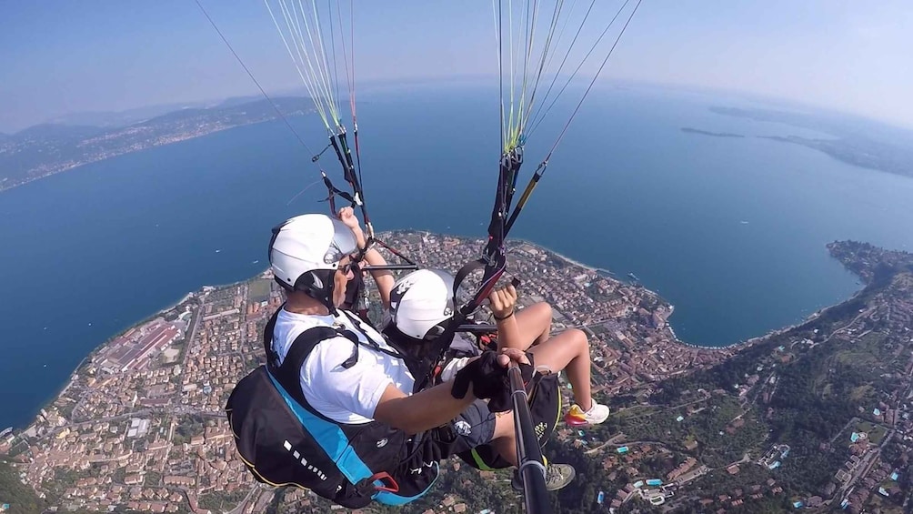 Two people paragliding over a coastal city with a view of the sea and mountains. 1