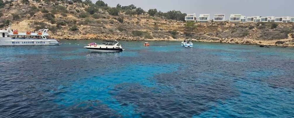 A boat named 'MELI LAGOON CHRONO' on a clear blue sea, with a rocky coastline and buildings in the background. 3