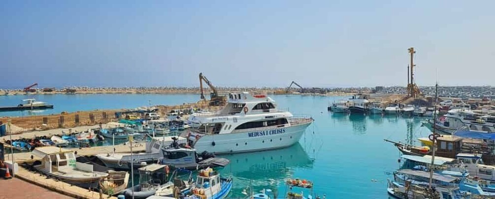 A marina with multiple boats docked, a prominent white ship named 'MEDUSA CRUISES,' and a clear blue sky. 2