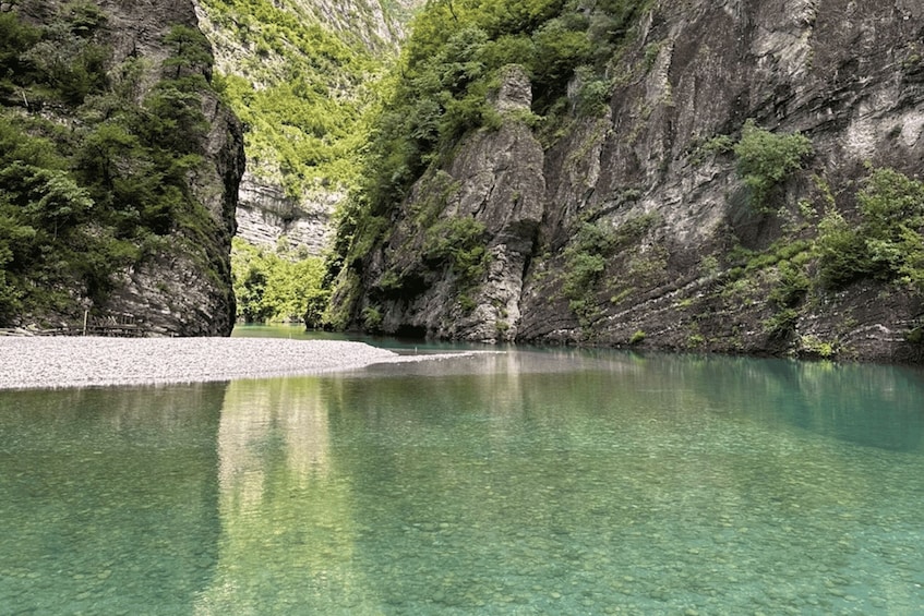 A clear lake surrounded by rocky cliffs with sparse vegetation. 2