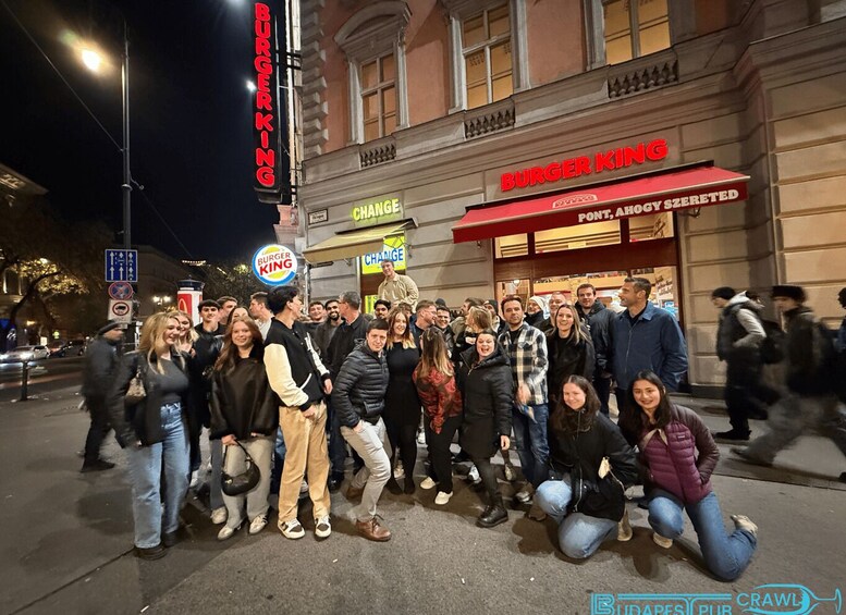 A group of people posing in front of a Burger King restaurant at night. 1