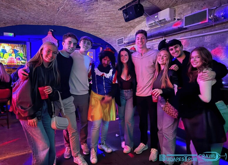A group of people in a dimly lit room with a stone ceiling and air conditioning units. 3