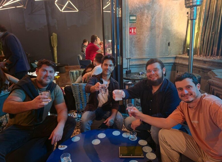 A group of people sitting around a table with drinks, in a room with a cactus and geometric lighting. 5