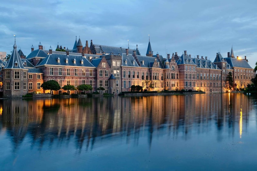 A historic building with multiple spires and a calm body of water reflecting its architecture. 1