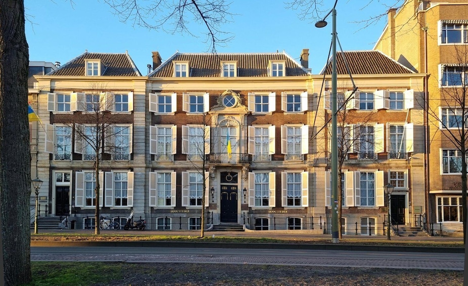 A row of traditional European townhouses with white shutters, a central entrance, and a clear sky. 2
