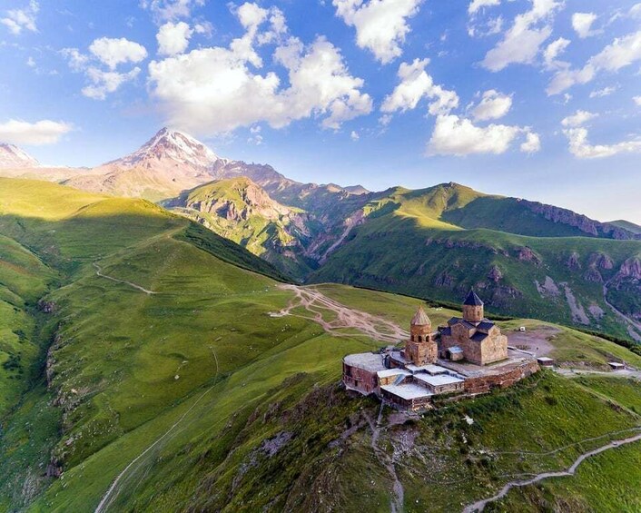 A mountainous landscape with a historic building complex on a hill. 3