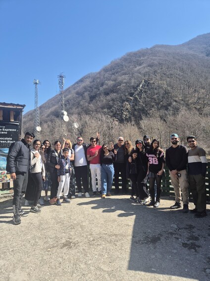 A group of people standing outdoors with a mountainous backdrop. 5