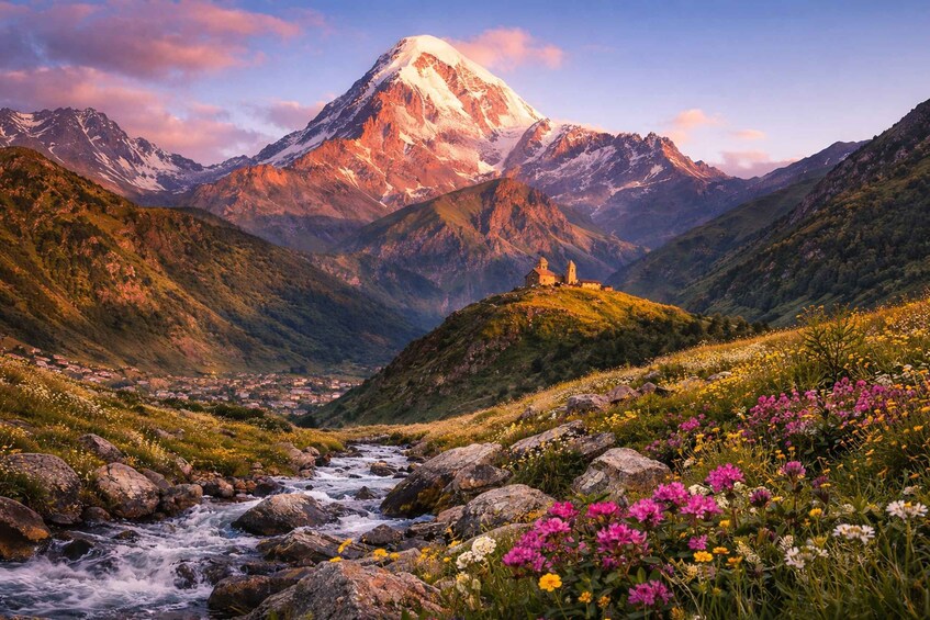 A mountain landscape with a snow-capped peak, a river, and colorful wildflowers. 1