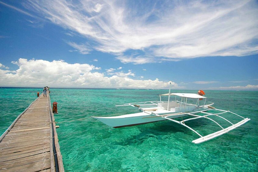 A wooden pier extending into turquoise waters with a boat moored at the end. 1