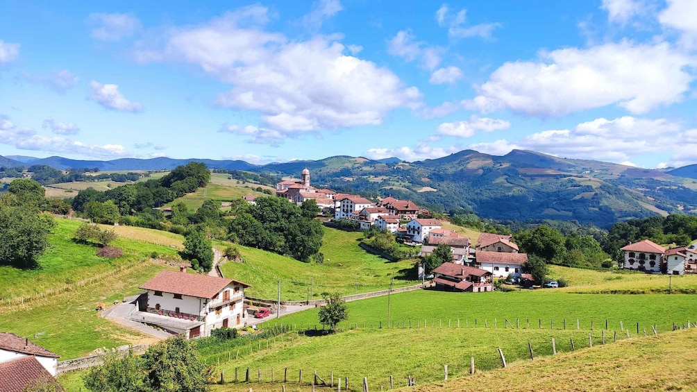 A village nestled in a valley with rolling hills in the background. 1