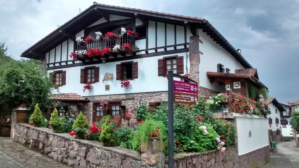 A traditional building with a stone facade, wooden shutters, and a balcony adorned with red flowers. 3