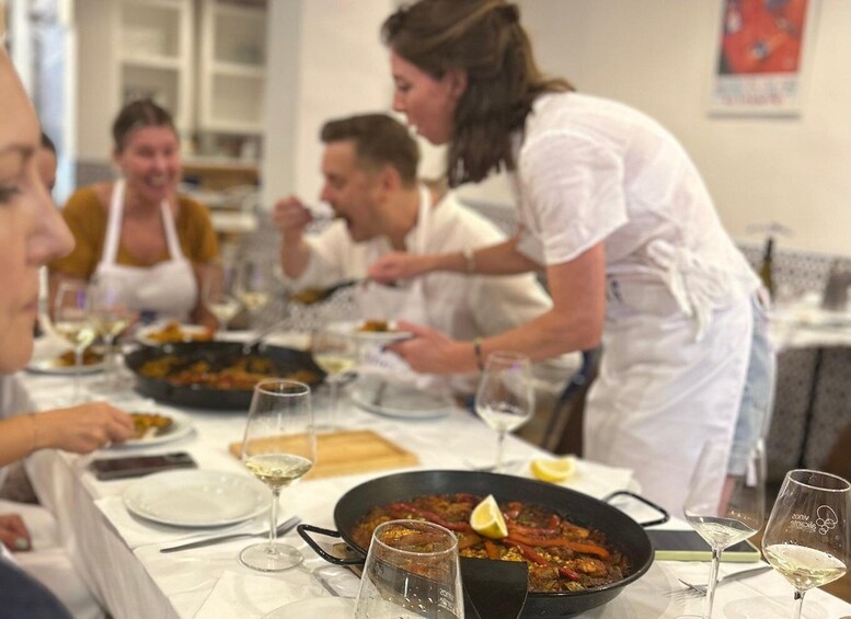 A group of people dining at a restaurant with a large pan of food on the table. 2