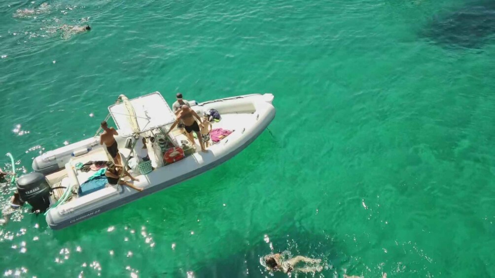 A small inflatable boat with people on board, floating on clear turquoise water. 2