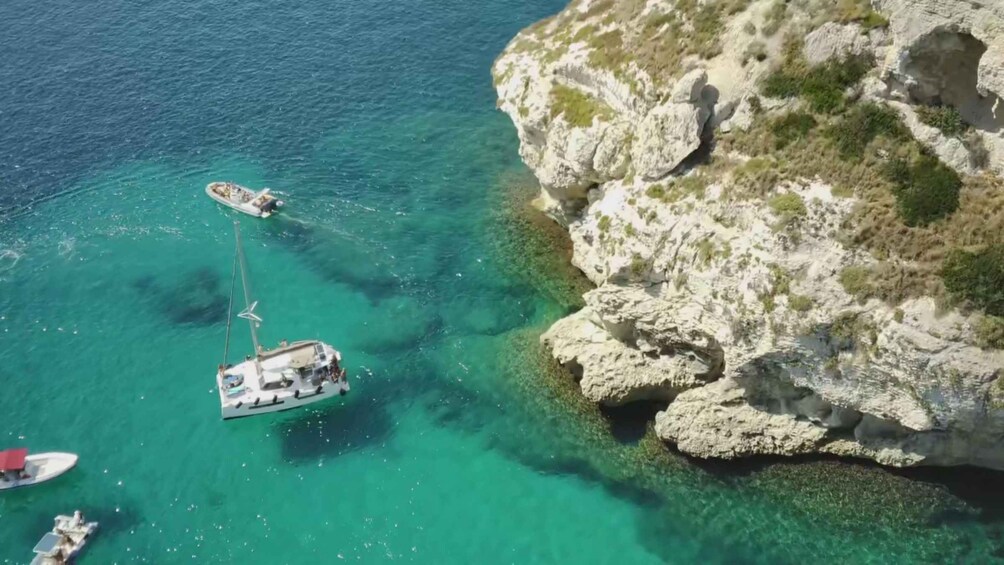 A coastal area with clear turquoise waters, rocky cliffs, and several boats anchored near the shore. 5