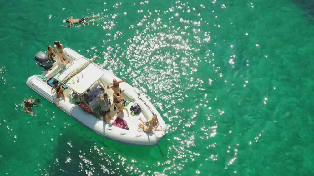 A group of people on a white inflatable boat in clear green water. 5