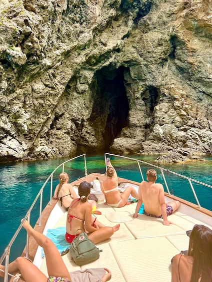 A group of people on a boat in a rocky cove with clear water. 4
