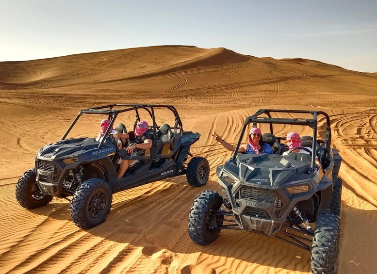 Two Polaris off-road vehicles on a sandy desert terrain with undulating dunes. 2