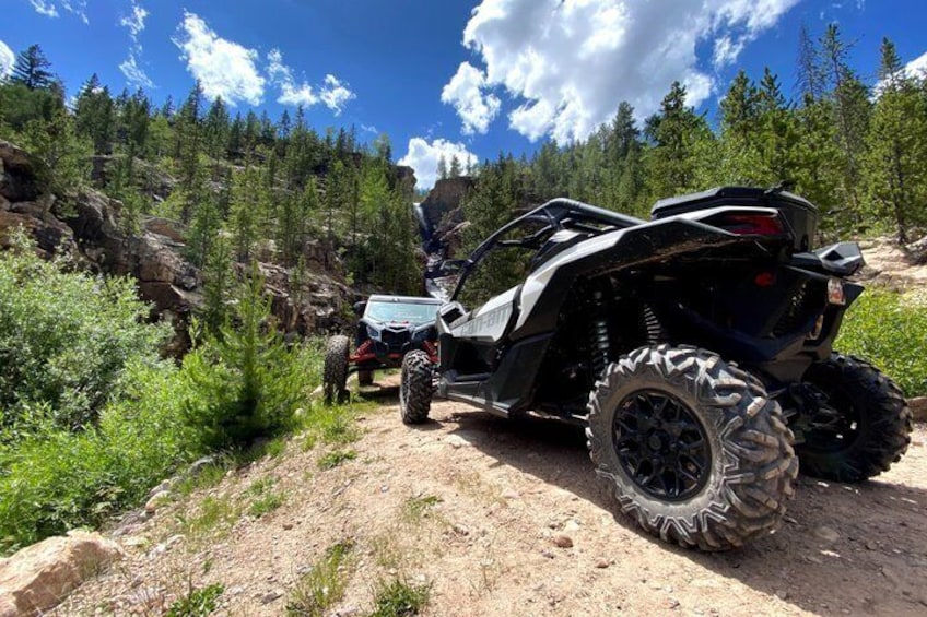 A quad bike on a dirt trail surrounded by trees and rocks. 1