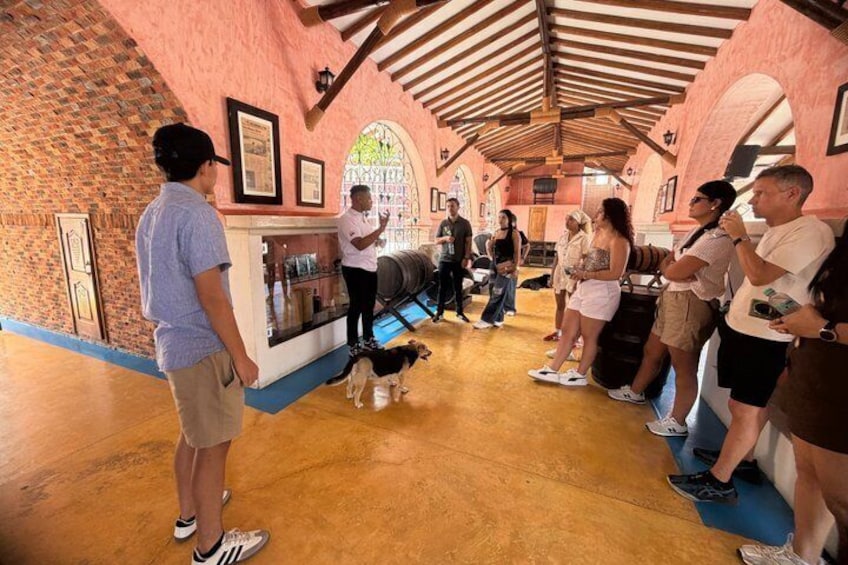 A group of people in a room with brick walls and a wooden ceiling, standing in a line, some looking at a display case. 2