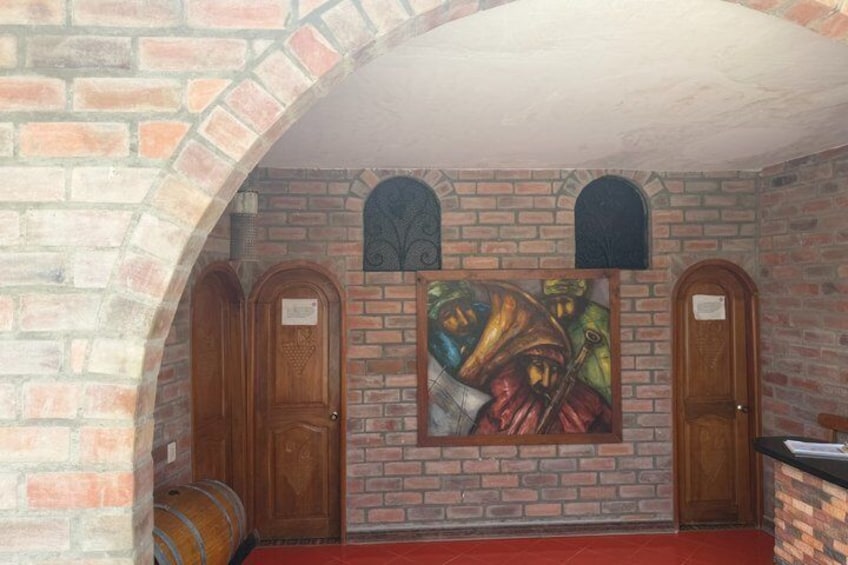 A brick wall with a mural, wooden doors, and a barrel. 4