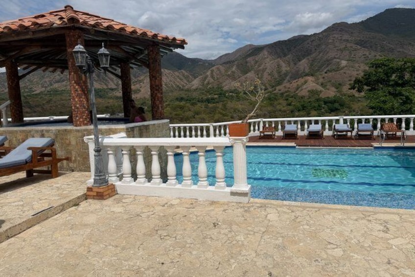 A pool with a white balustrade, lounge chairs, and a gazebo. 3
