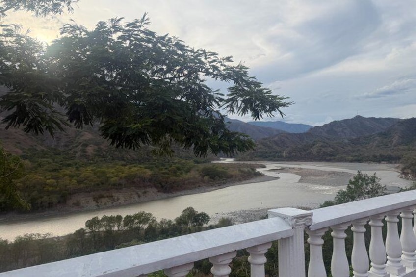 A river flowing through a mountainous landscape with a white balustrade in the foreground. 1