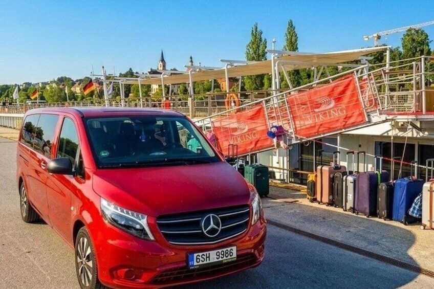 A red Mercedes-Benz van parked near a building with luggage. 2