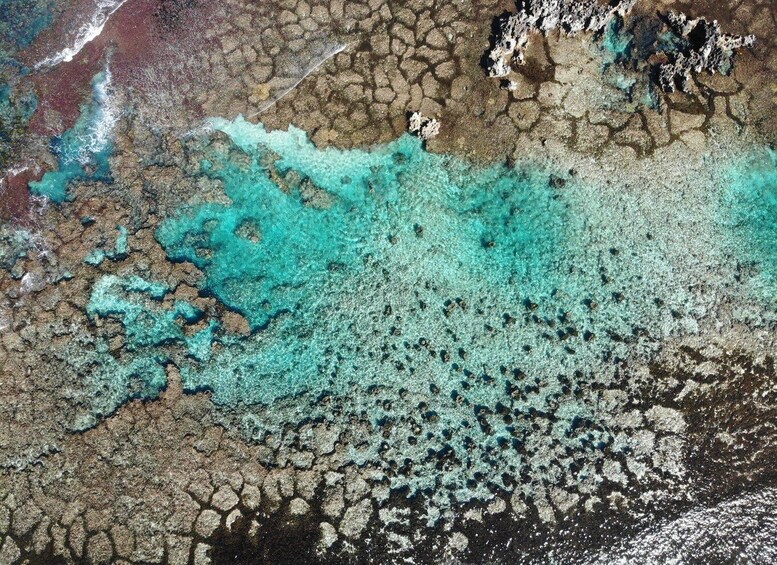 A coastal landscape with a mix of rocky terrain and turquoise water. 4