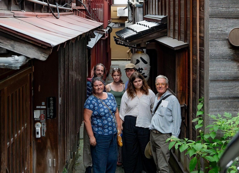 A narrow alleyway with wooden buildings, a red roof, and a person holding a camera. 5