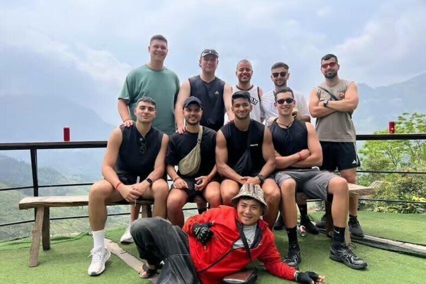 A group of people posing on a bench with a mountainous landscape in the background. 3