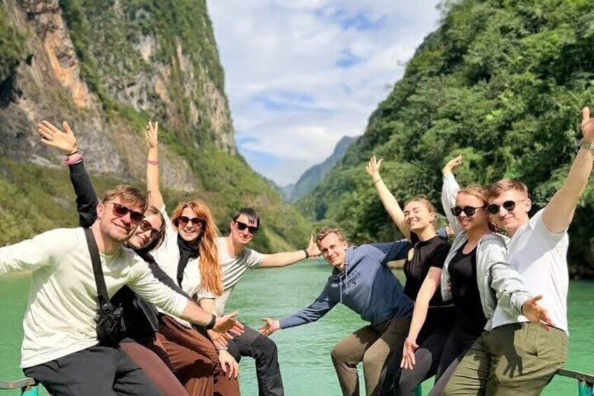 A group of people on a boat in a green river surrounded by cliffs. 2